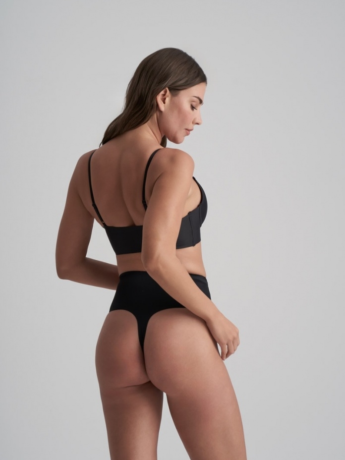 Bye Bra lengvos kompresijos besiūlės formuojančios tanga kelnaitės INVISIBLE MID WAIST THONG BLACK